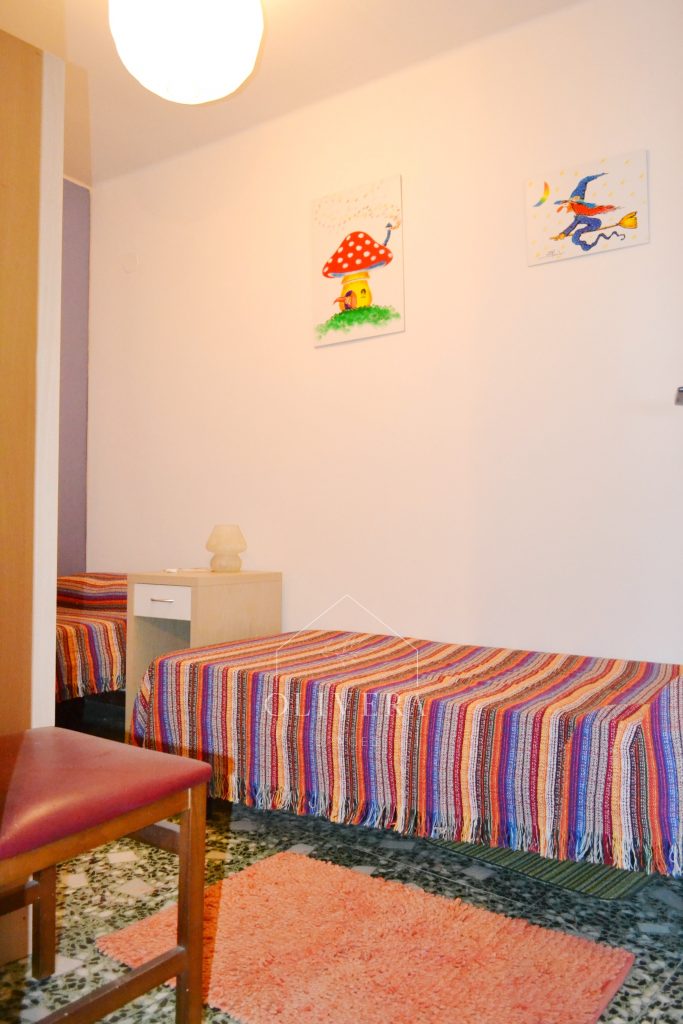 Habitación 3 con dos camas, mesitas, armario y espejo. Pared pintada de color lila.