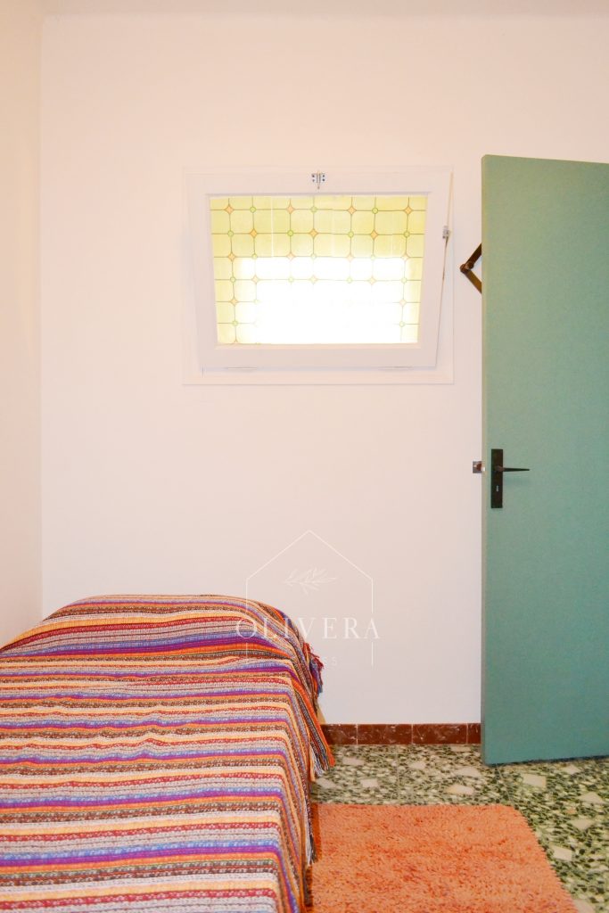 Habitación 3 con dos camas, mesitas, armario y espejo. Pared pintada de color lila.