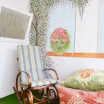 Galería o terraza interior muy luminosa, con césped artificial, butacas y mural pintado en la pared.