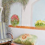 Galería o terraza interior muy luminosa, con césped artificial, butacas y mural pintado en la pared.