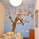 Habitación 1 con cama doble, armario y mesita. Mural de un almendro pintado en la pared.